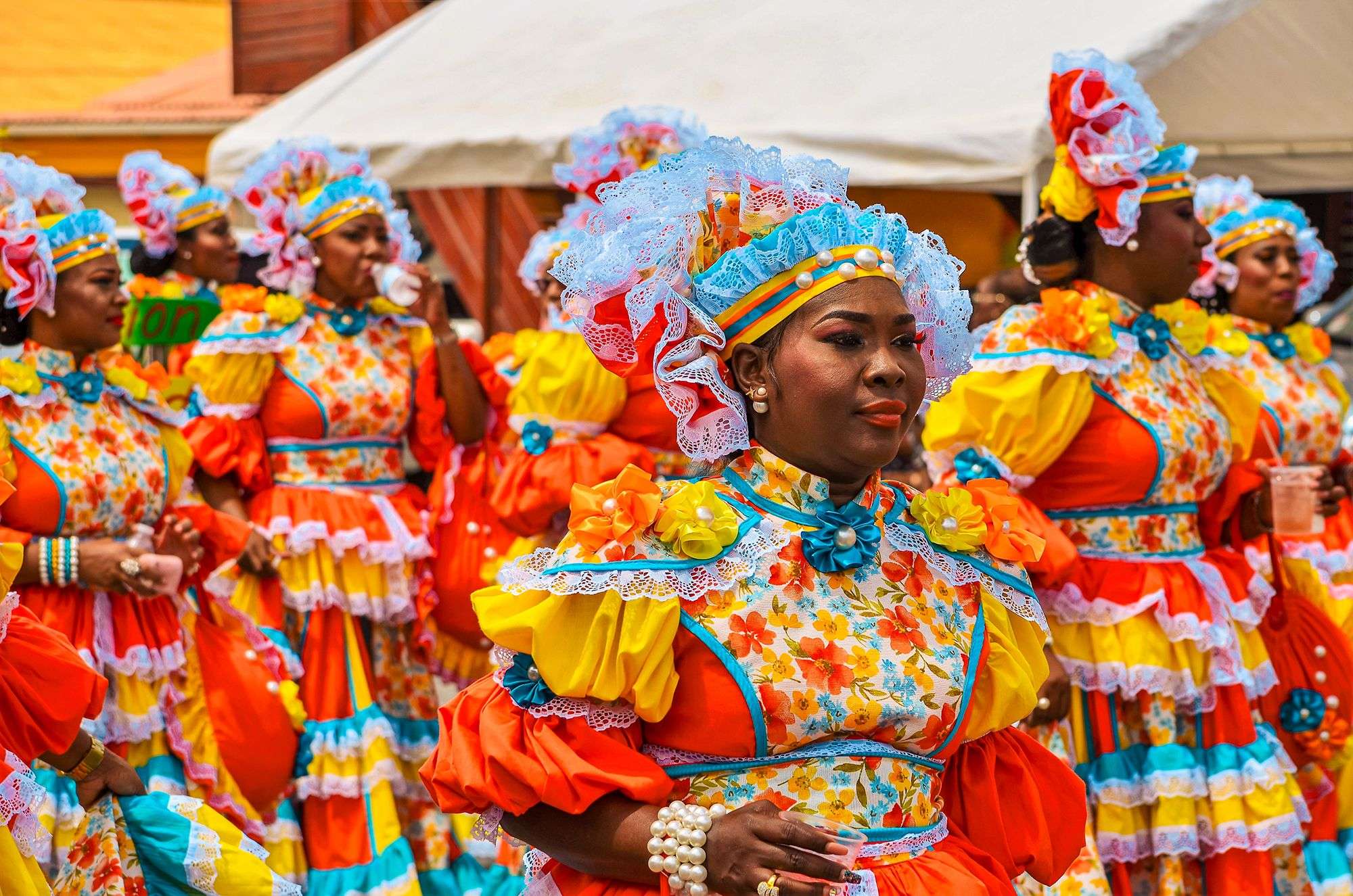 Seven women in brilliantly colored matching costumes marching in a carnival parade in Curacao